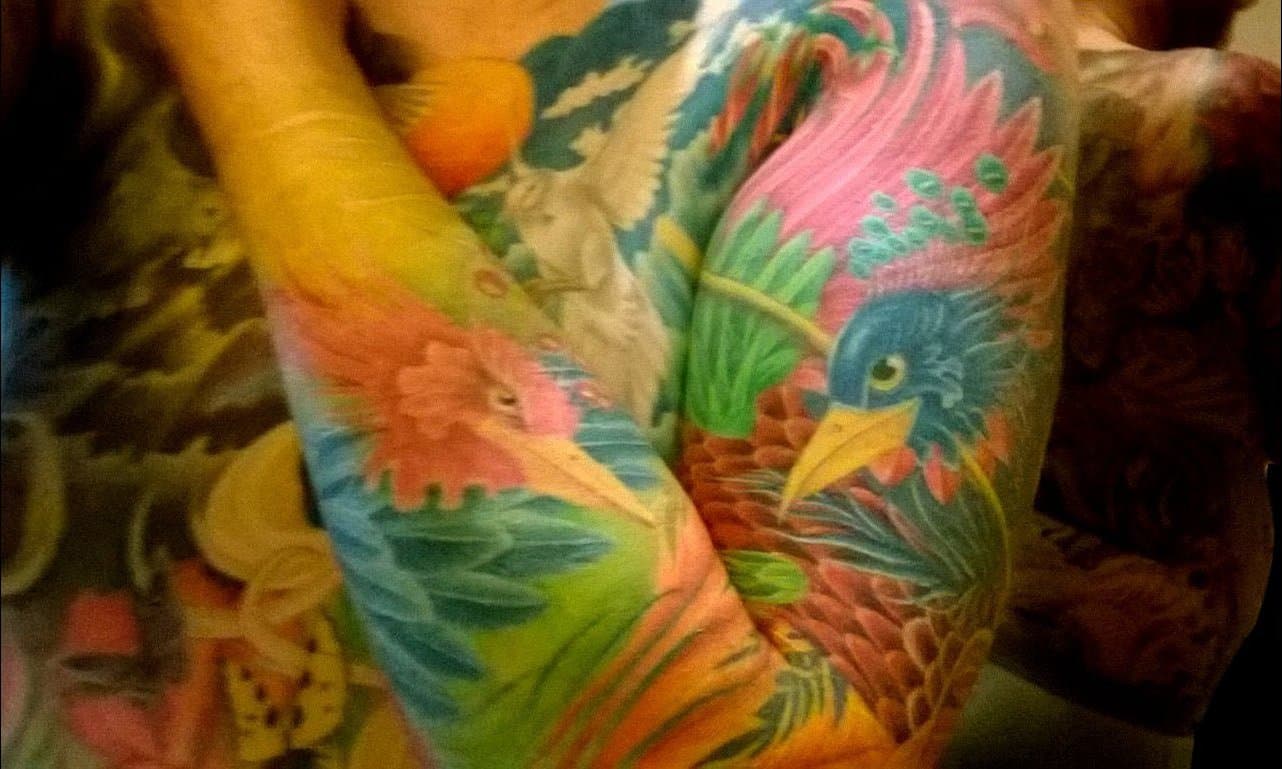 Close up of a colorful phoenix sleeve tattoo on an arm